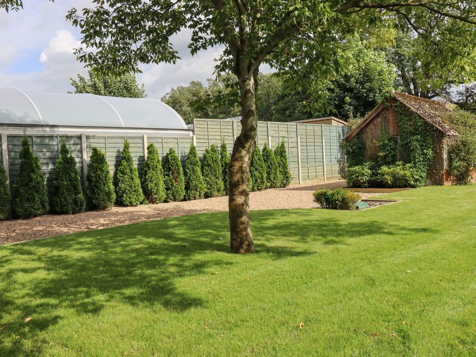 A garden with a shed, plants, and a fence at Cottage by the River in Burnley