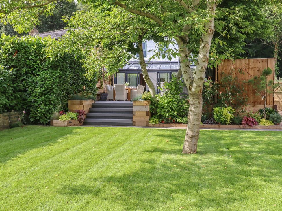 A garden with steps leading to seating area at Cottage by the River Burnley