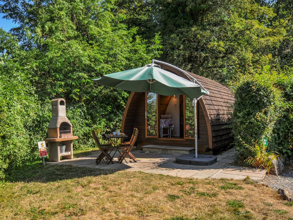A garden with a wooden cottage and outdoor seating at Yar Tor in Tavistock