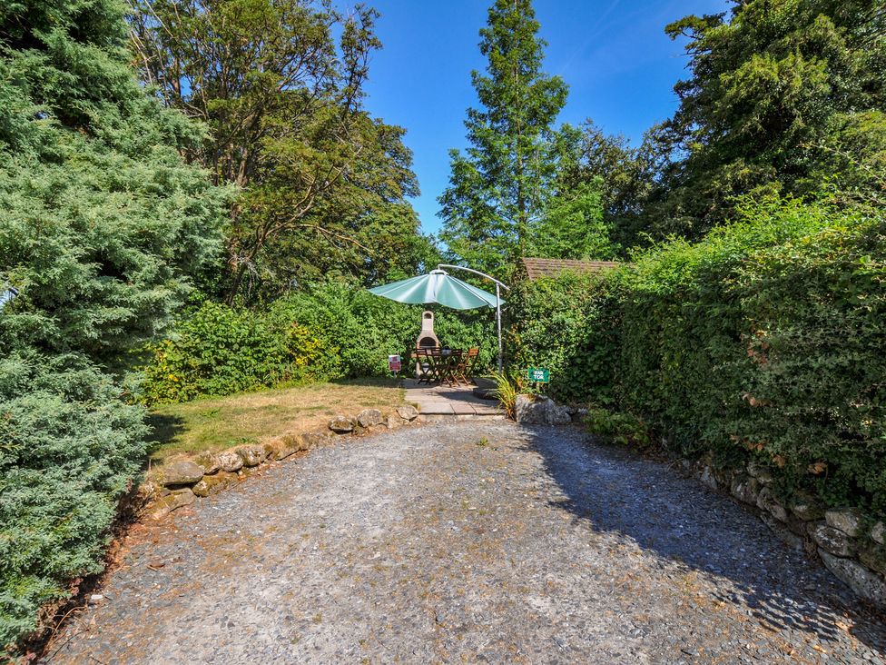 A garden with a table and chairs under an umbrella at Yar Tor in Tavistock