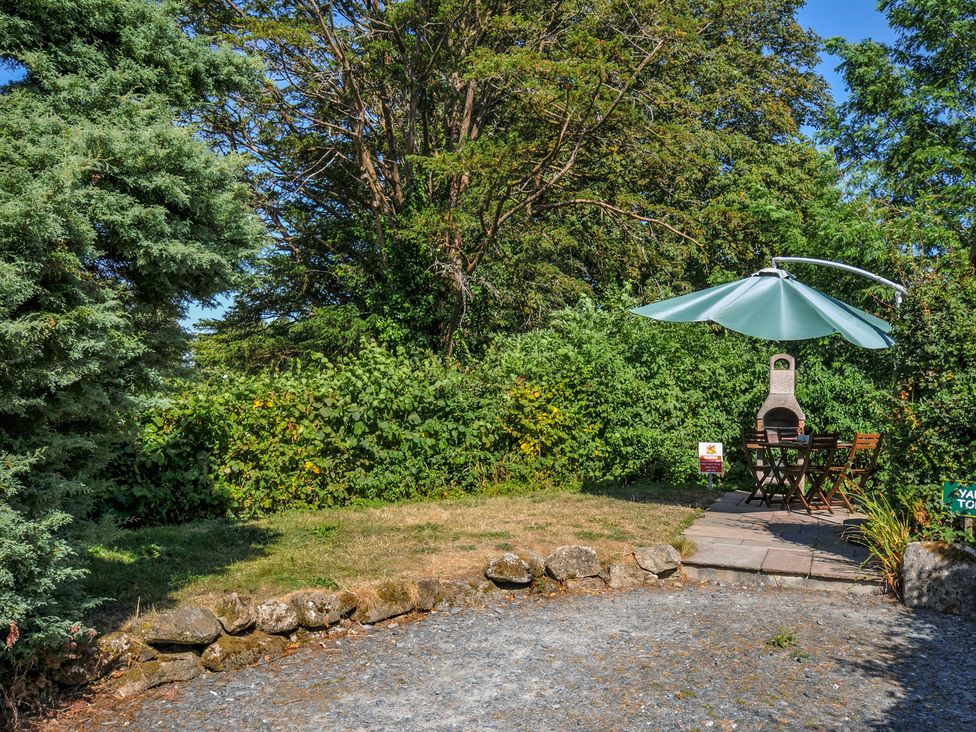 A garden area with a table and chairs under an umbrella at Yar Tor in Tavistock