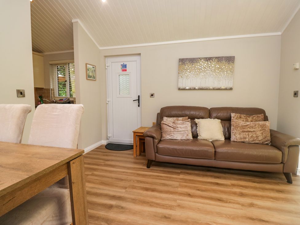 A living room with a sofa and dining table at Fir Tree Lodge, White Cross bay on Windermere, Troutbeck Bridge