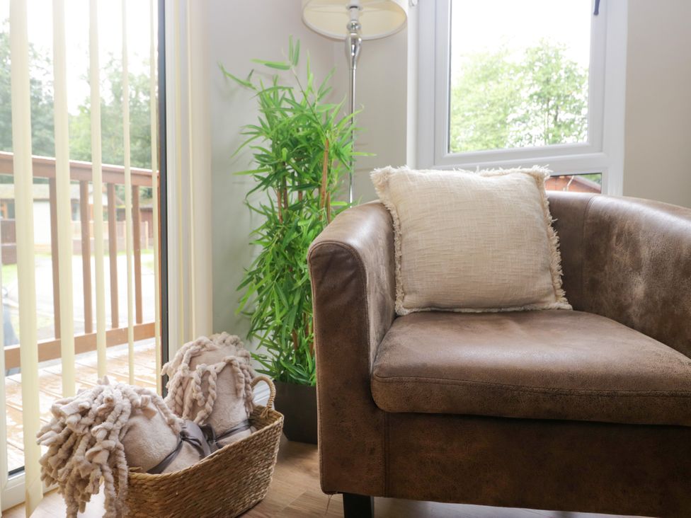 A living room with an armchair, pillow, and plant at Fir Tree Lodge, White Cross bay on Windermere, Troutbeck Bridge