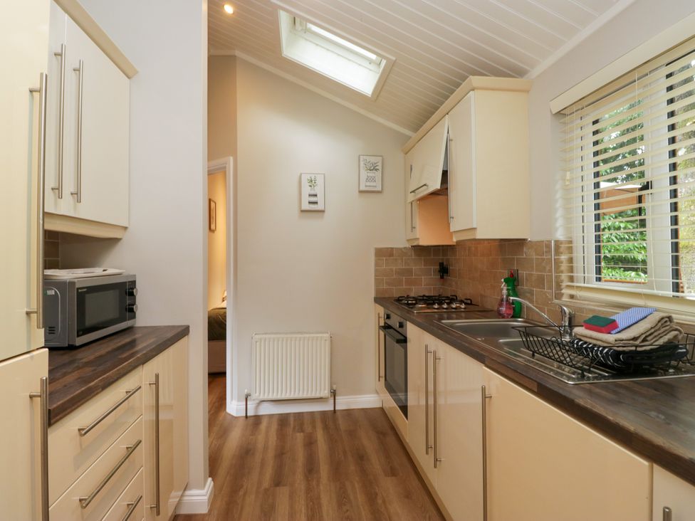 A kitchen with a stove and microwave at Fir Tree Lodge in White Cross bay on Windermere, Troutbeck Bridge