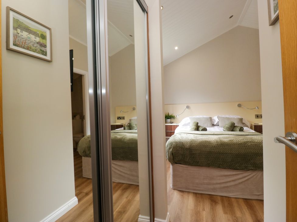 A bedroom with a bed and mirror at Fir Tree Lodge in White Cross bay on Windermere, Troutbeck Bridge