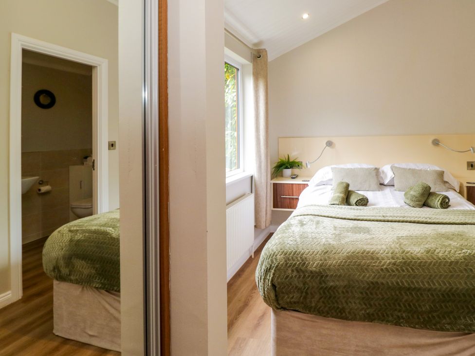 A bedroom with a bed and an adjoining bathroom at Fir Tree Lodge, White Cross bay on Windermere, Troutbeck Bridge