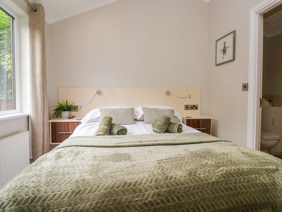 A bedroom with a bed and a bedside table at Fir Tree Lodge in White Cross bay on Windermere, Troutbeck Bridge