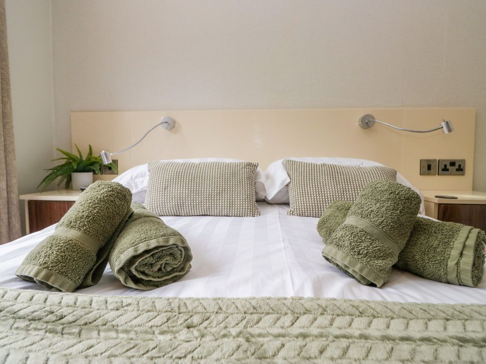 A bedroom with towels arranged on a bed at Fir Tree Lodge in White Cross bay on Windermere, Troutbeck Bridge
