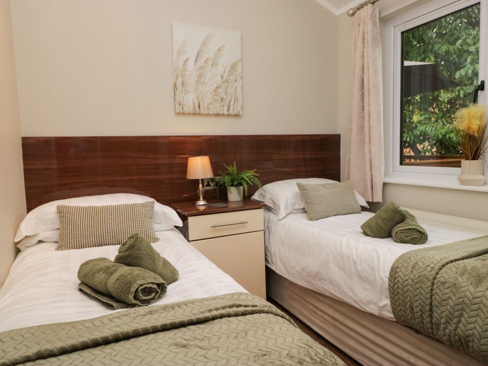 A bedroom with two beds and a window at Fir Tree Lodge, White Cross bay on Windermere, Troutbeck Bridge