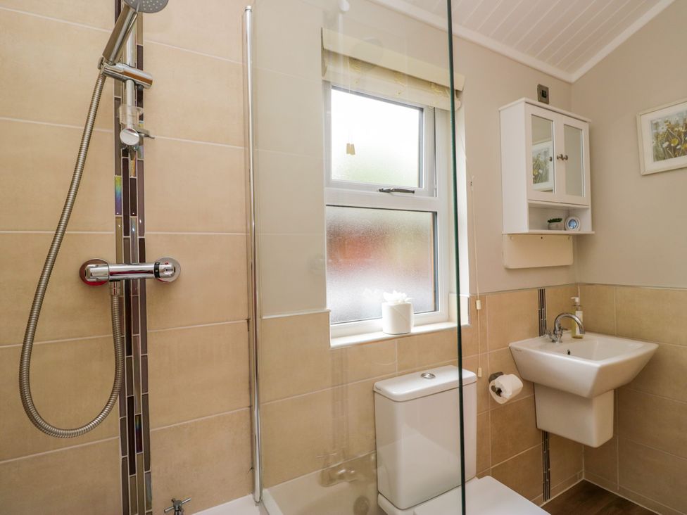 A bathroom featuring a shower, toilet, sink and window at Fir Tree Lodge, White Cross bay on Windermere, Troutbeck Bridge