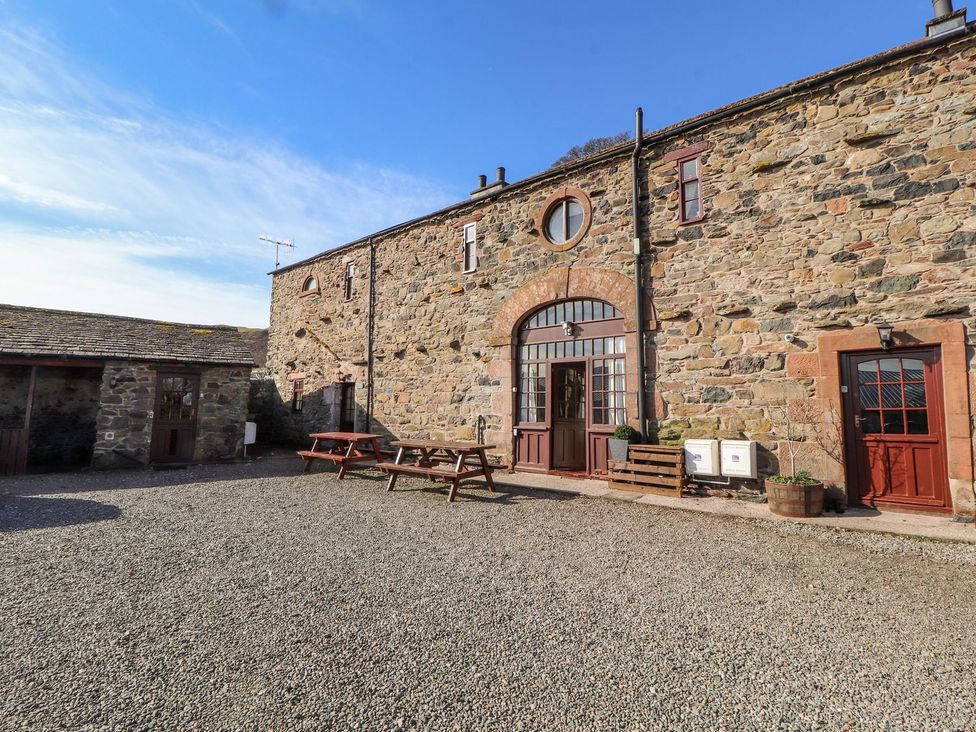 An outdoor area with stone walls and seating at Mellfell Cottage near Watermillock