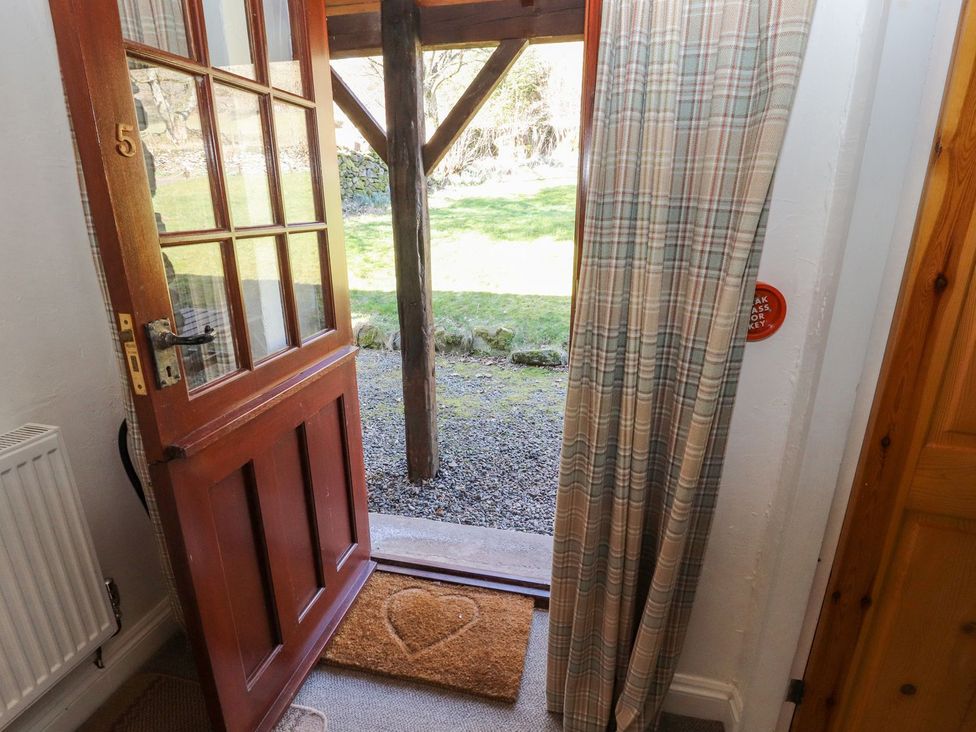 An entrance with an open door and welcome mat at Mellfell Cottage near Watermillock