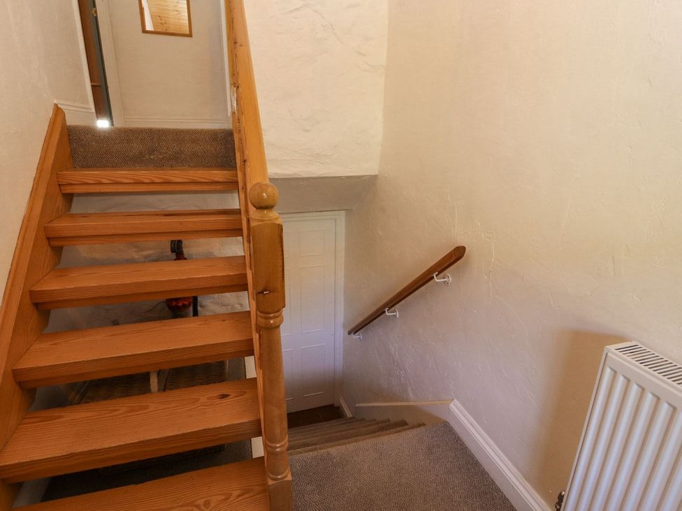 Stairs with wooden handrail and door at Mellfell Cottage near Watermillock