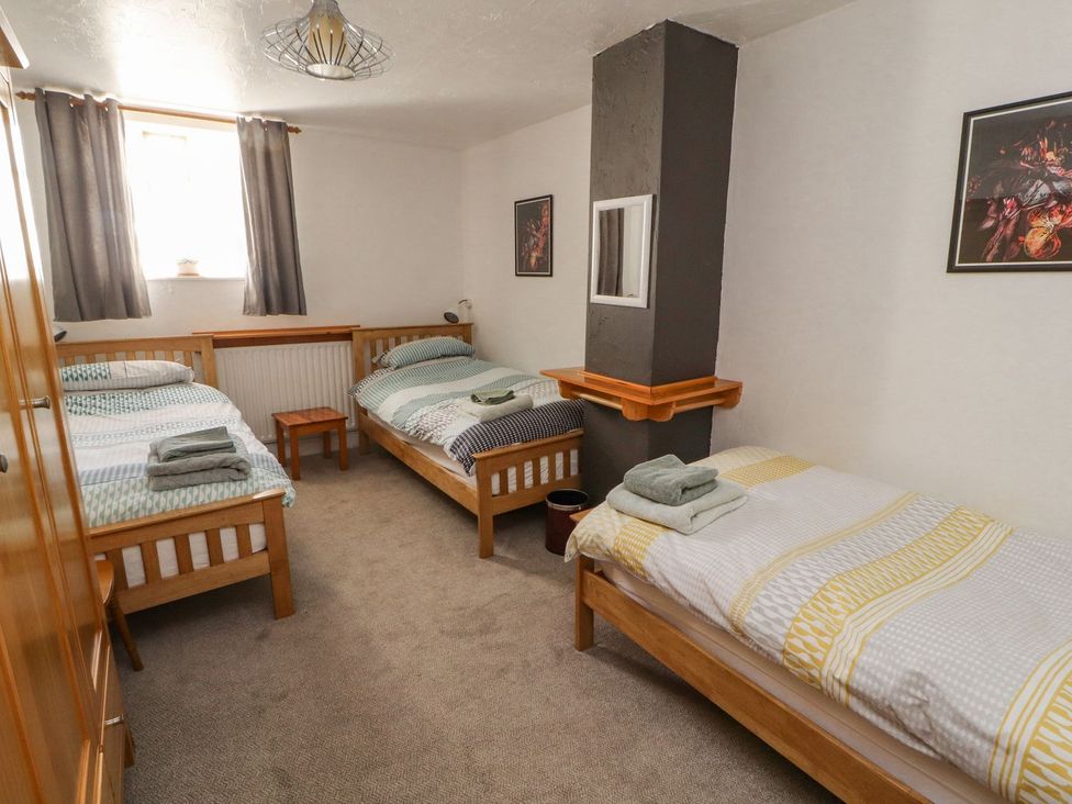 A bedroom with three single beds and a wooden table at Mellfell Cottage near Watermillock