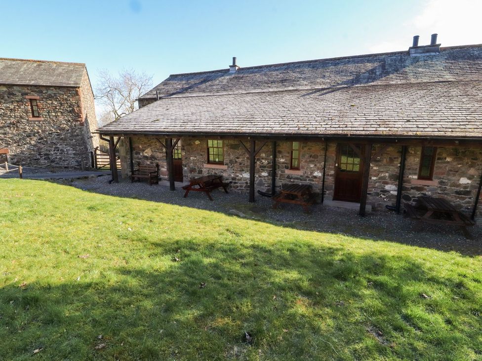 An outdoor area with stone buildings and seating at Mellfell Cottage near Watermillock