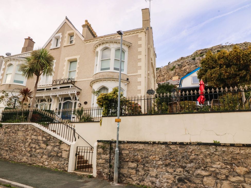An exterior view of a house with a garden and palm trees at Tudno Lodge in Llandudno