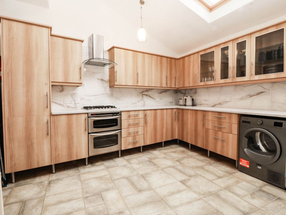 A kitchen with wooden cabinets and appliances at Tudno Lodge in Llandudno