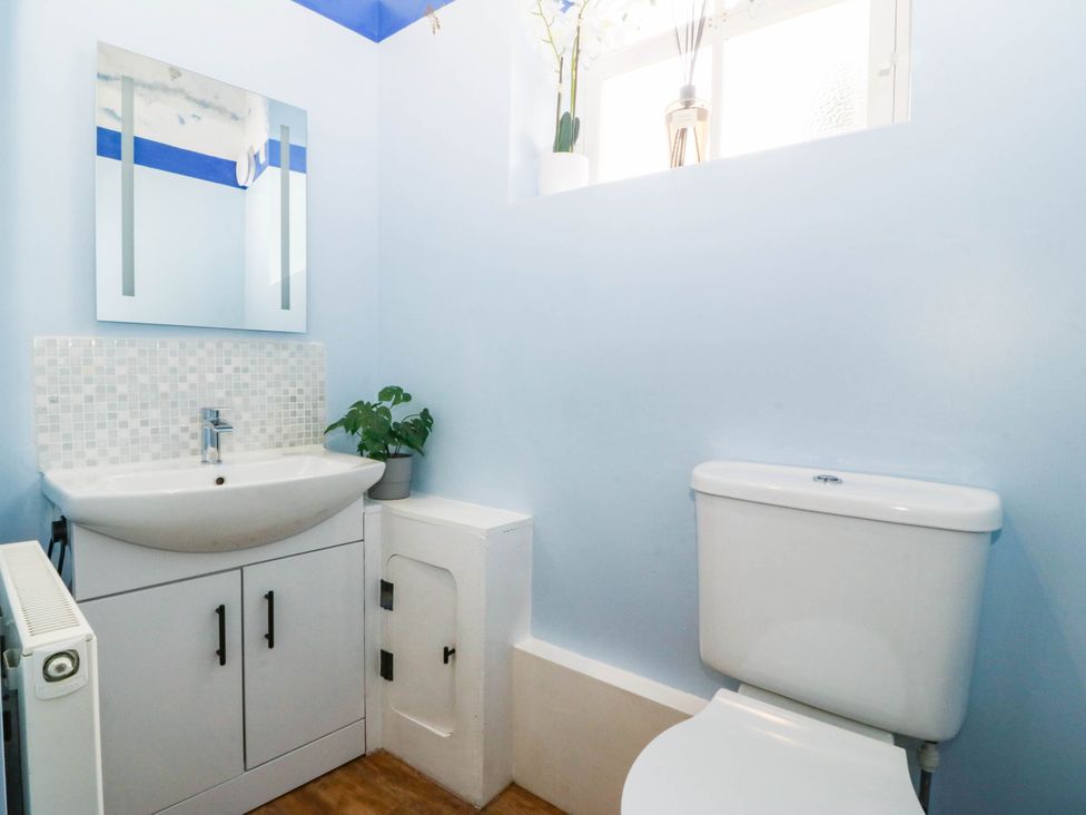 A bathroom with a sink, toilet and mirror at Tudno Lodge in Llandudno
