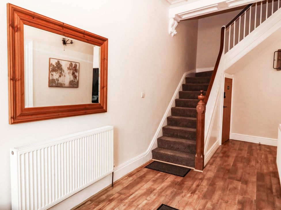 A hallway with a staircase and a mirror at Tudno Lodge Llandudno