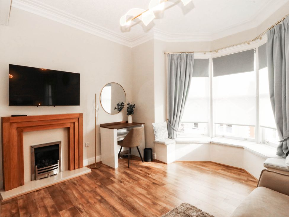 A living room with a television, fireplace, and desk at Tudno Lodge in Llandudno