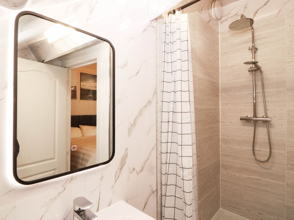 A bathroom with a shower, mirror, and sink at Tudno Lodge in Llandudno
