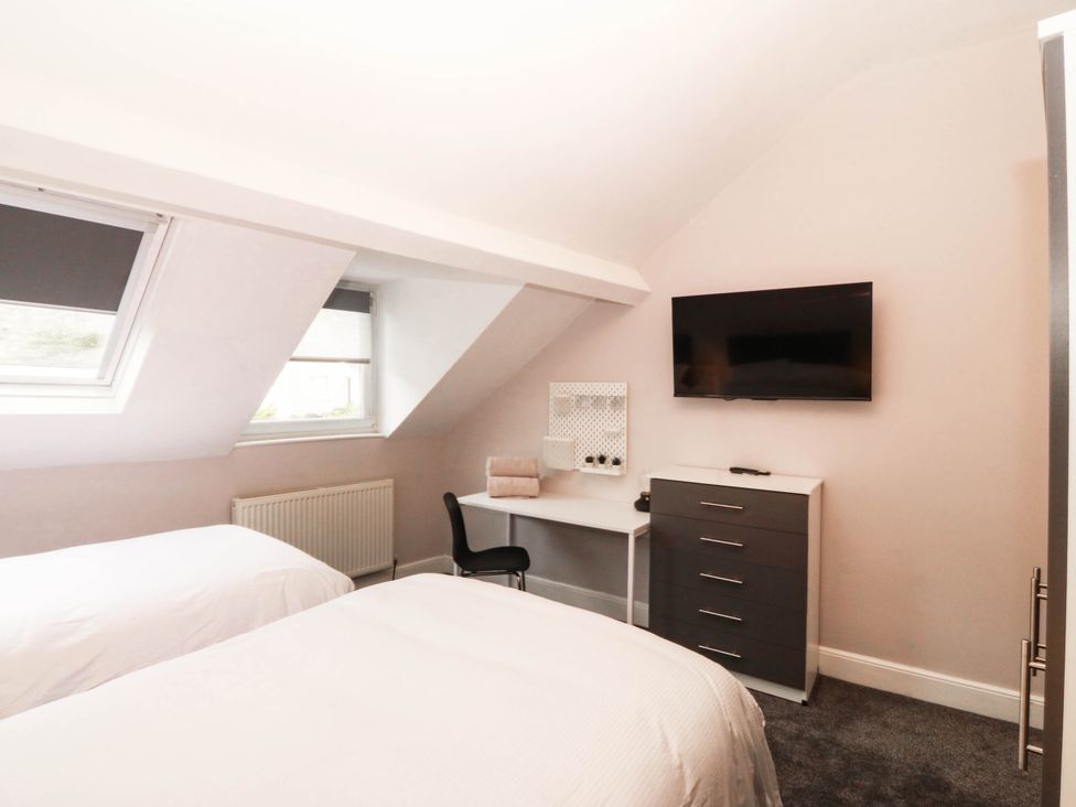 A bedroom with two beds and a desk at Tudno Lodge in Llandudno