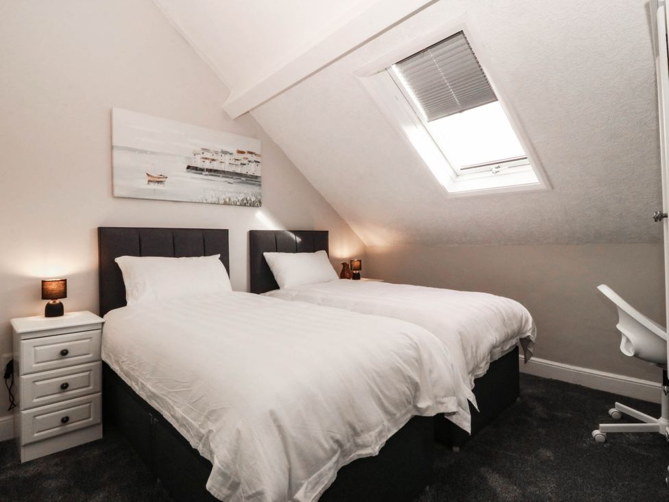 A bedroom with two single beds and a nightstand at Tudno Lodge Llandudno