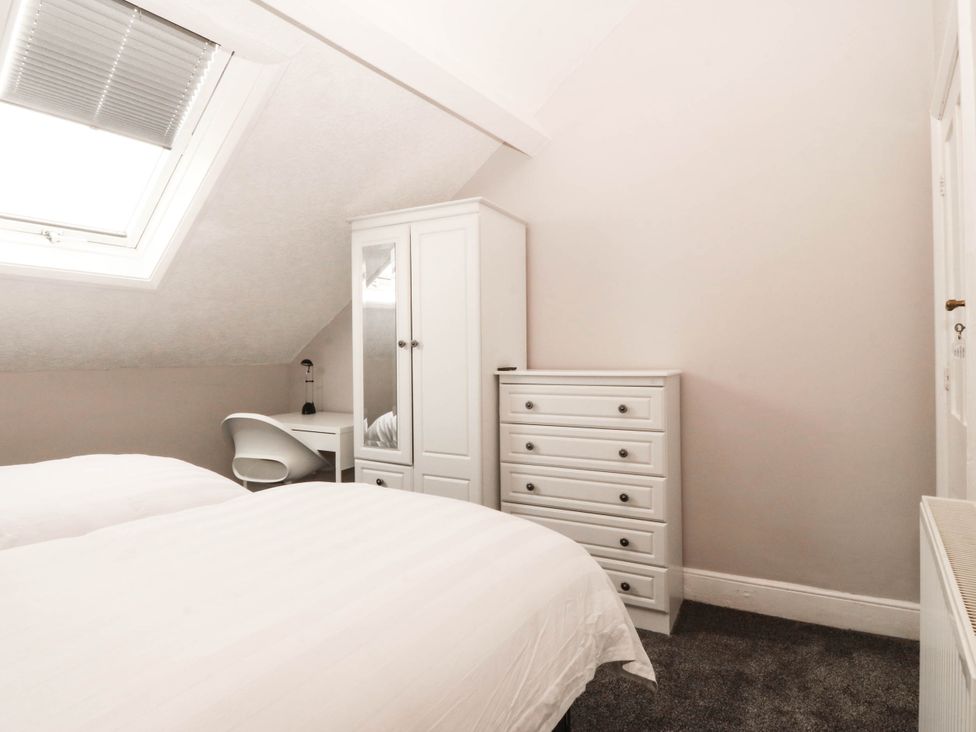 A bedroom with a bed, wardrobe, dresser, and desk at Tudno Lodge in Llandudno