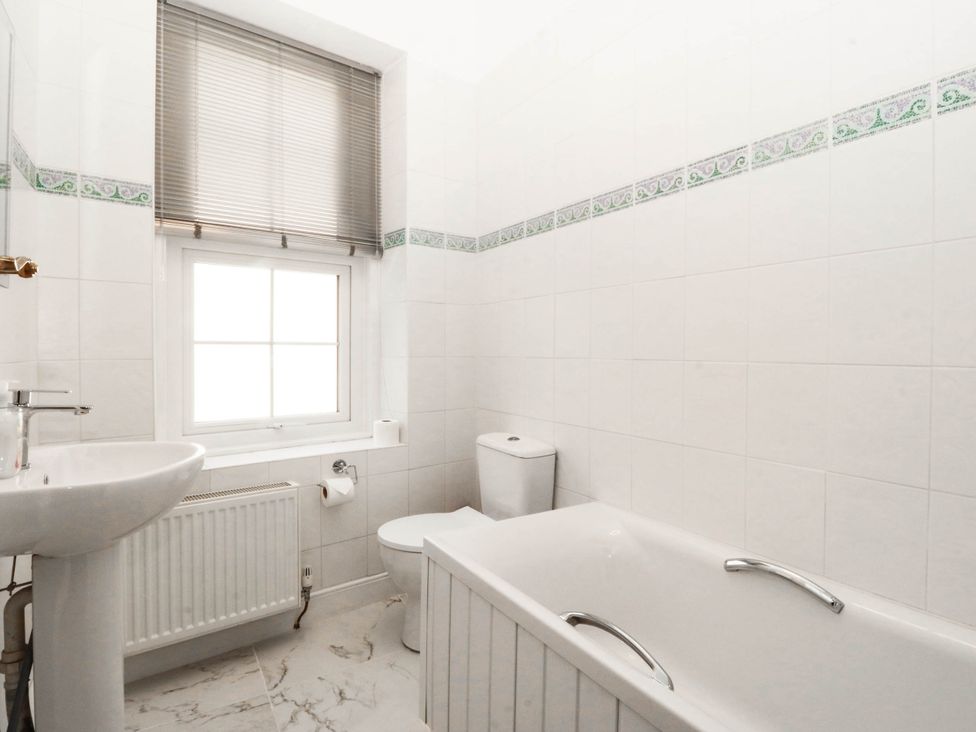 A bathroom with a sink, bathtub, toilet and window at Tudno Lodge in Llandudno