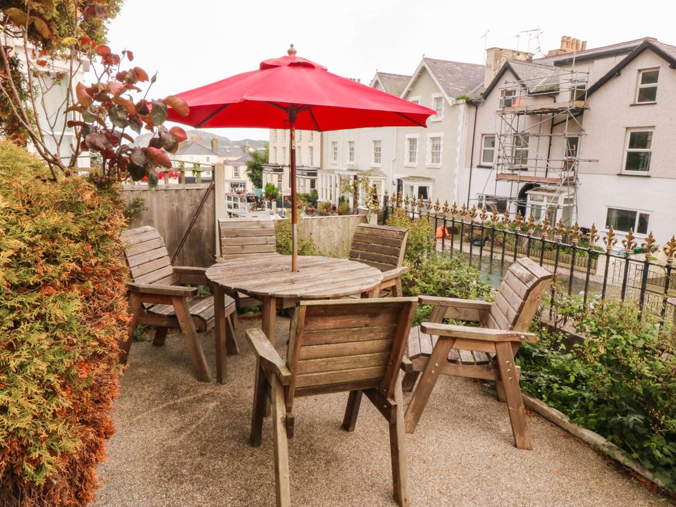 A garden with a table and chairs under an umbrella at Tudno Lodge in Llandudno
