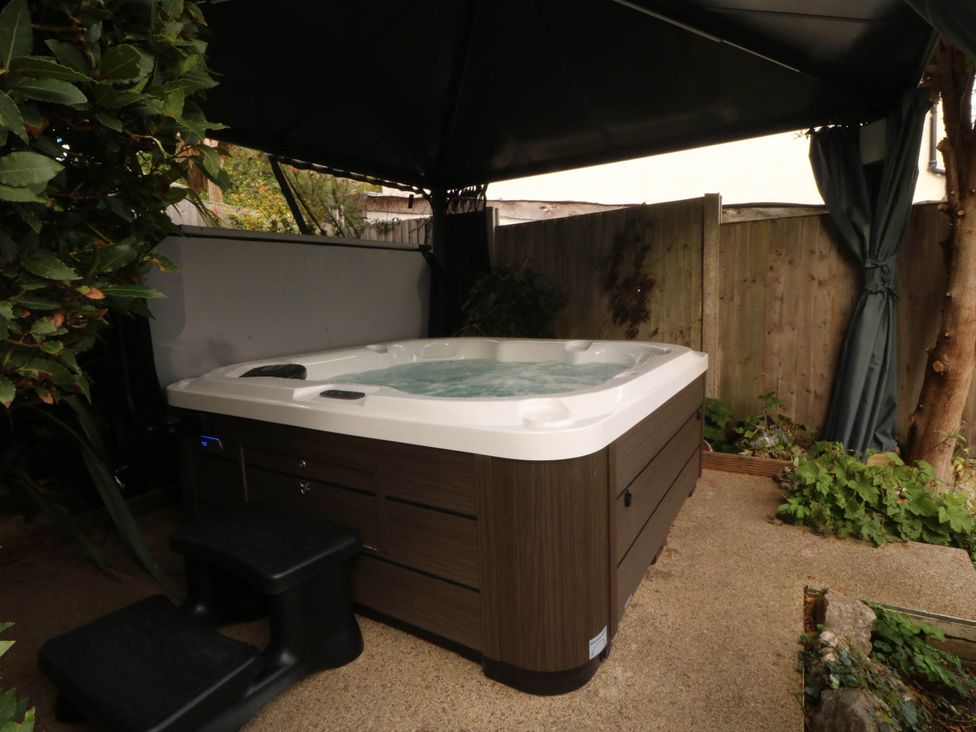 An outdoor area with hot tub under a canopy at Tudno Lodge in Llandudno