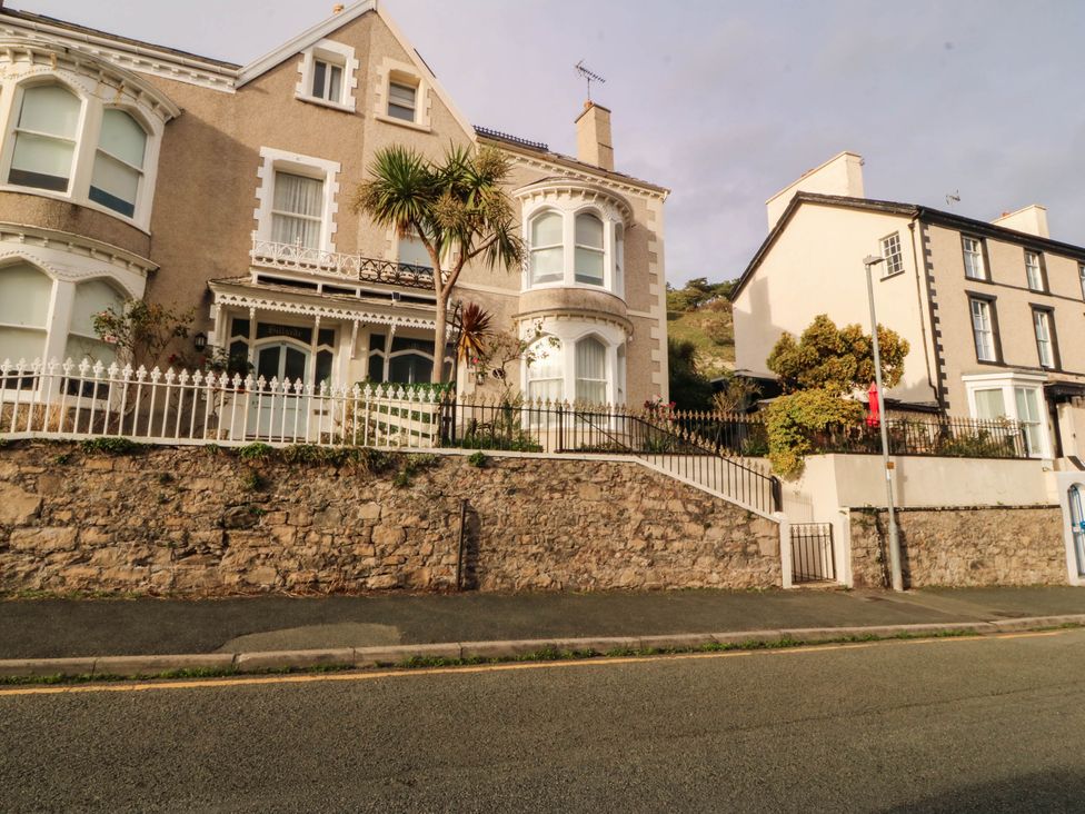 A house with palm trees and a stone wall at Tudno Lodge in Llandudno