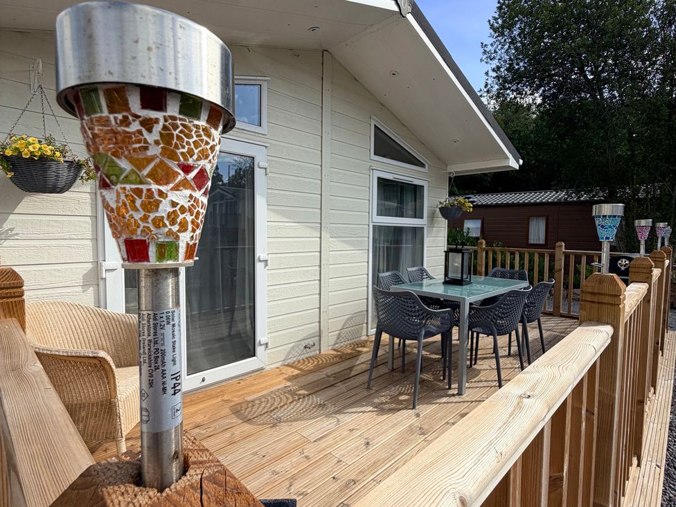 An outdoor deck with table and chairs at Boutique Lodge in Cheriton Bishop