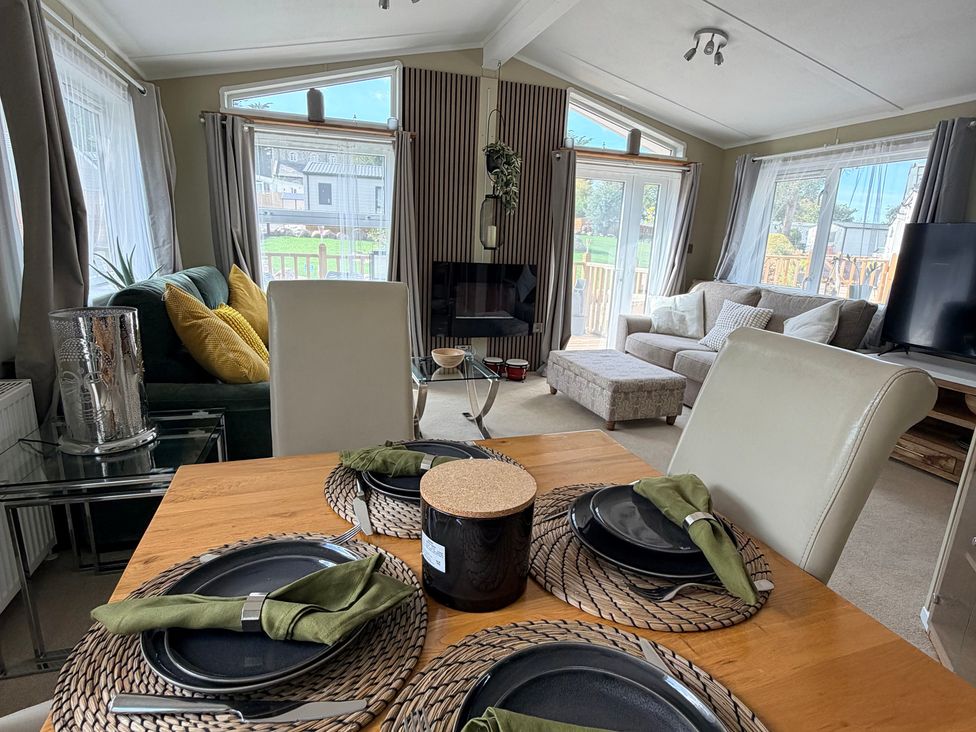 A living room with a dining table and television at Boutique Lodge in Cheriton Bishop