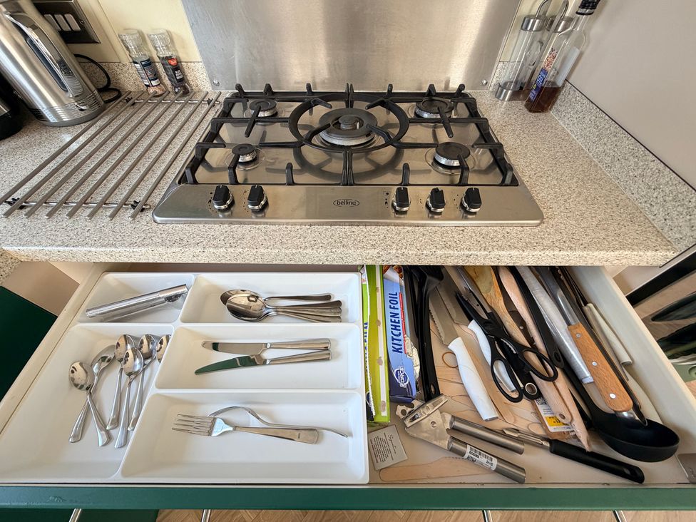 A kitchen with a cooktop and utensils in a drawer at Boutique Lodge in Cheriton Bishop