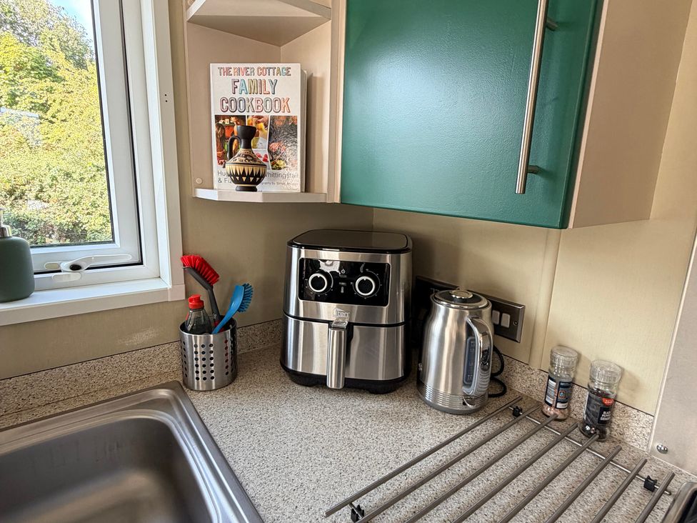 A kitchen with an air fryer, kettle, and a family cookbook at Boutique Lodge in Cheriton Bishop