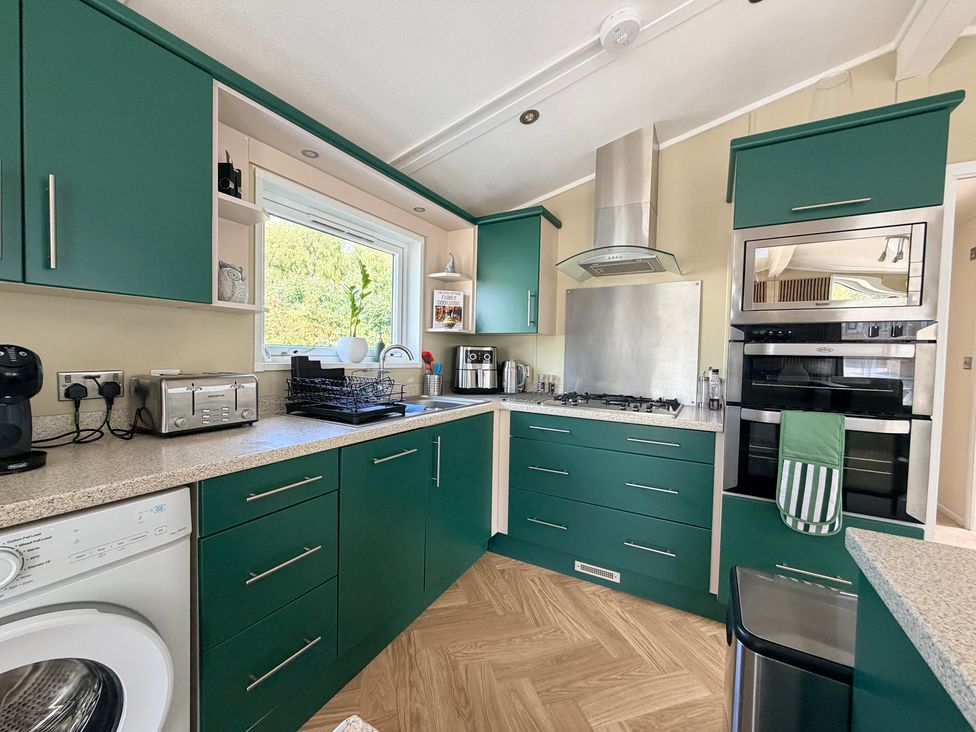 A kitchen with green cabinets and appliances at Boutique Lodge in Cheriton Bishop