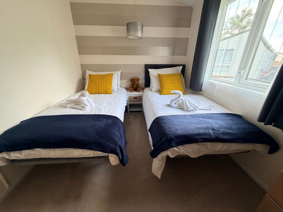 A bedroom with two beds and a nightstand at Boutique Lodge in Cheriton Bishop