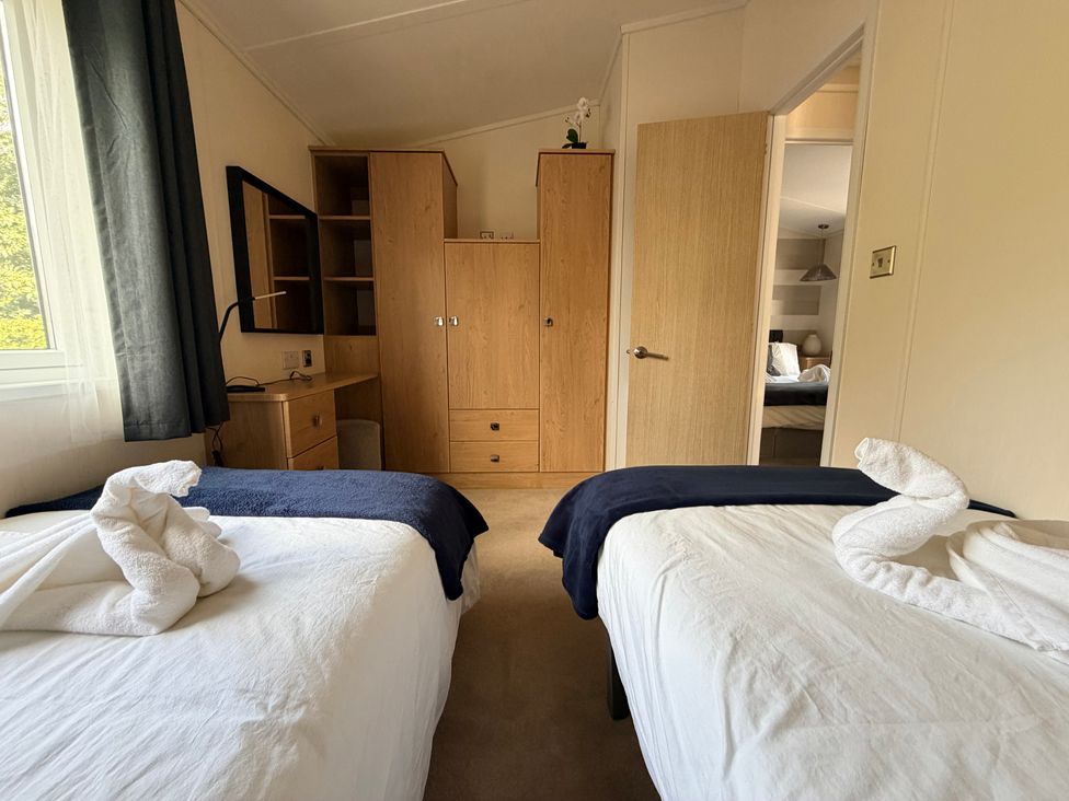 A bedroom with two beds and a wooden drawer unit at Boutique Lodge in Cheriton Bishop