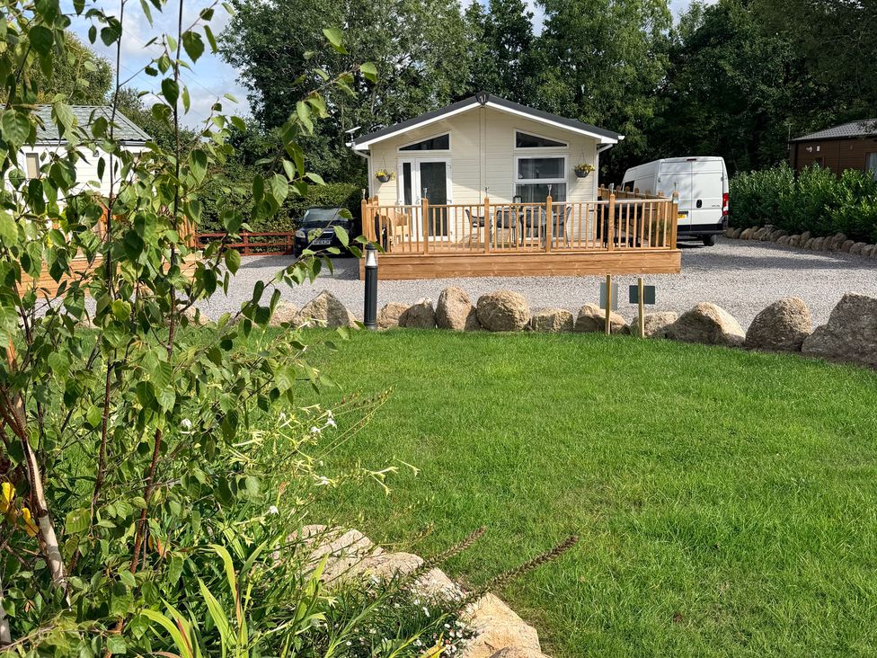 A lodge with deck and gravel parking at Boutique Lodge in Cheriton Bishop