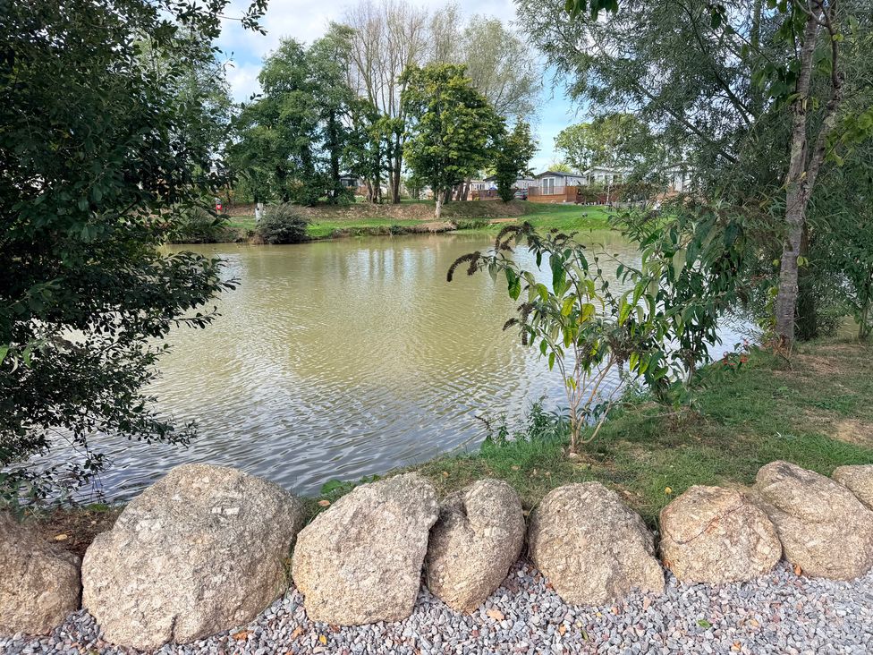 A scenic view of a pond surrounded by foliage at Boutique Lodge in Cheriton Bishop