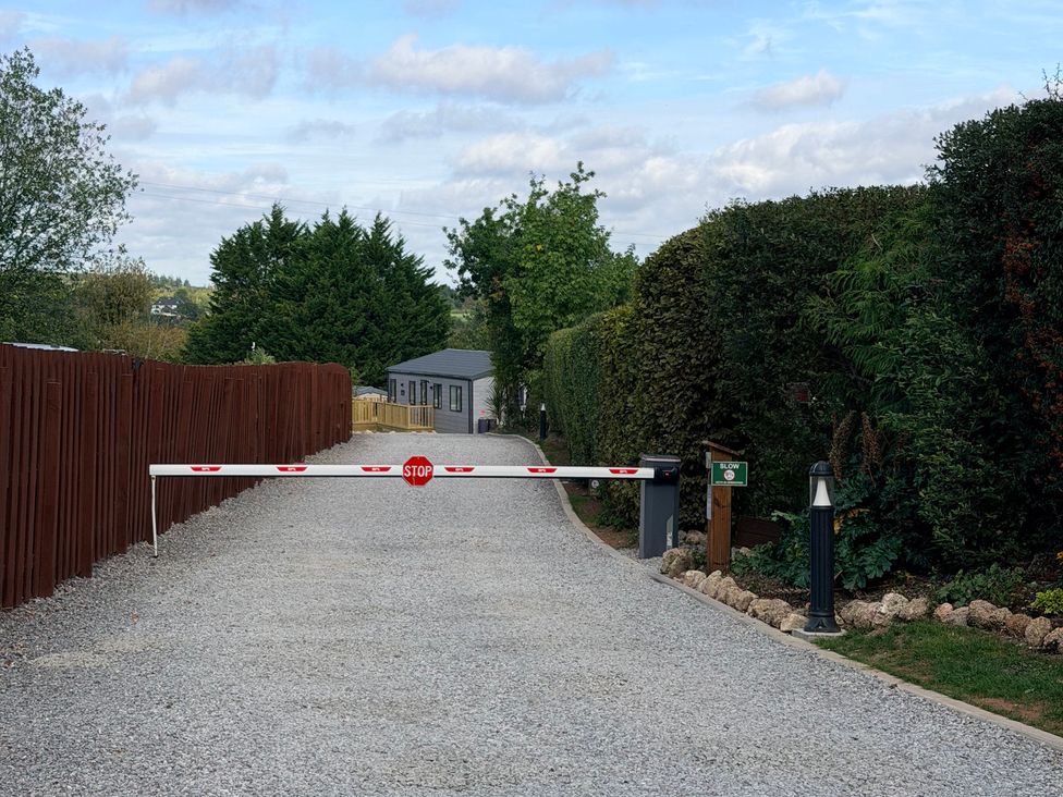 A gravel driveway with a security gate at Boutique Lodge in Cheriton Bishop