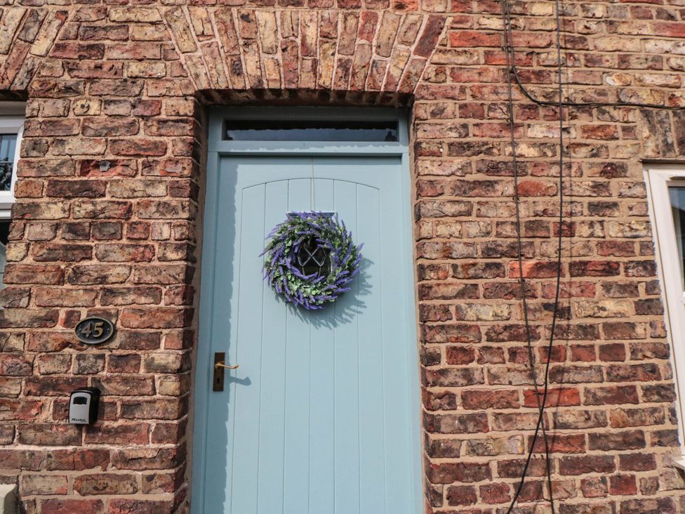A blue door with a wreath and brick wall at 45 St. Hildas Street in Sherburn