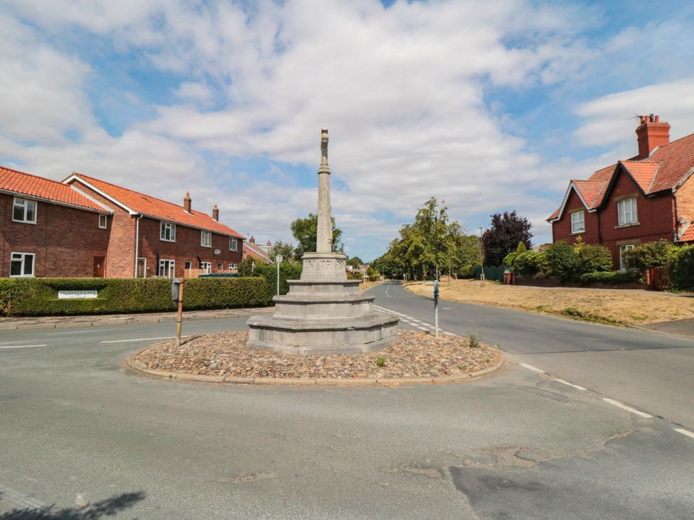A town monument at a roundabout with houses on either side at 45 St. Hildas Street in Sherburn