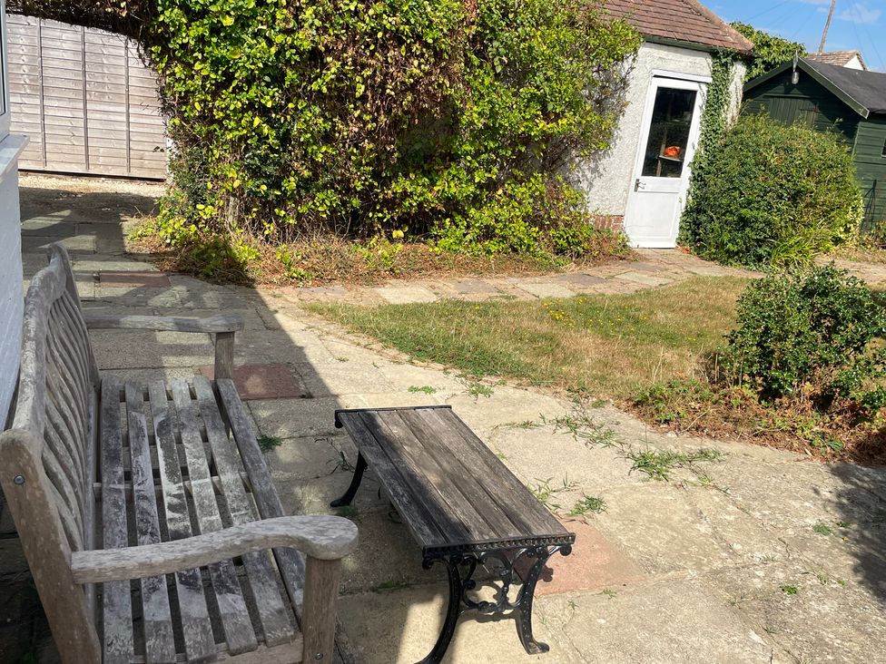 A garden with a bench and table at Summer Cottage in Rustington