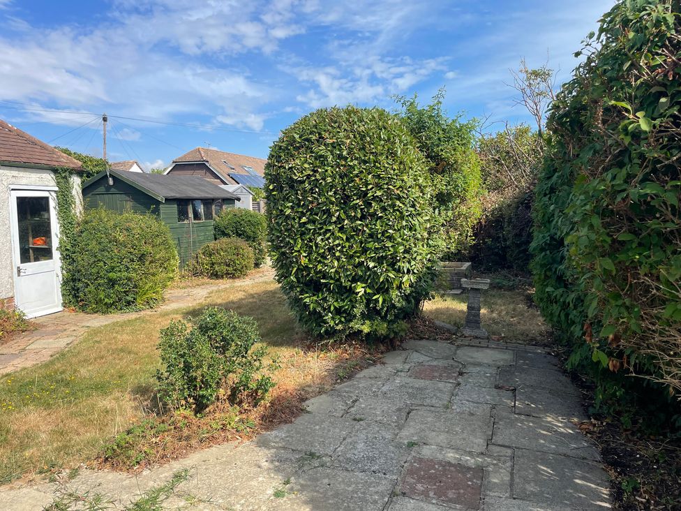 A garden with shrubs and a stone pathway at Summer Cottage in Rustington