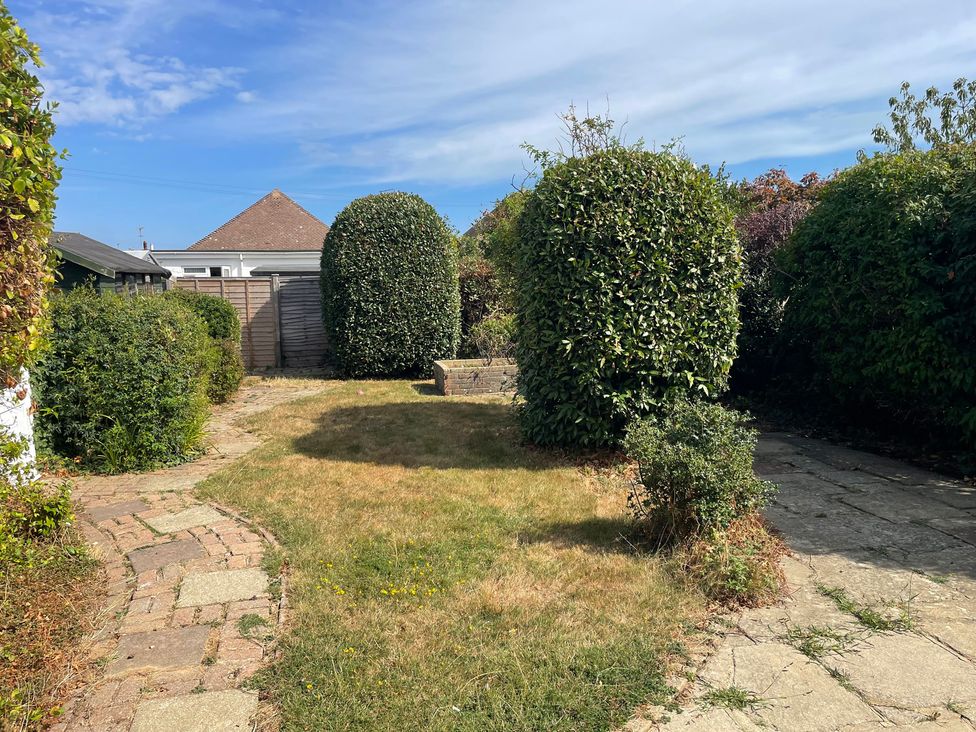 A garden with grass and hedges at Summer Cottage in Rustington
