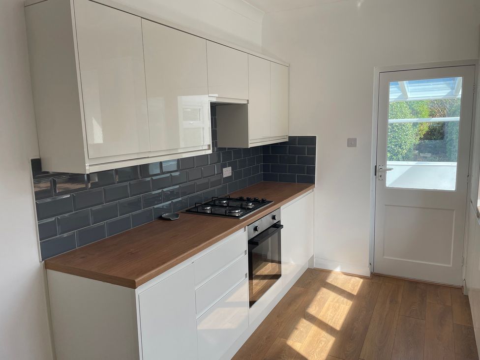 A kitchen with cabinets and a gas stove at Summer Cottage in Rustington