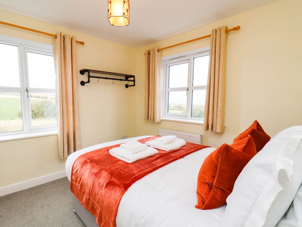 A bedroom with a bed and windows at 64 Derwent Road Whitby