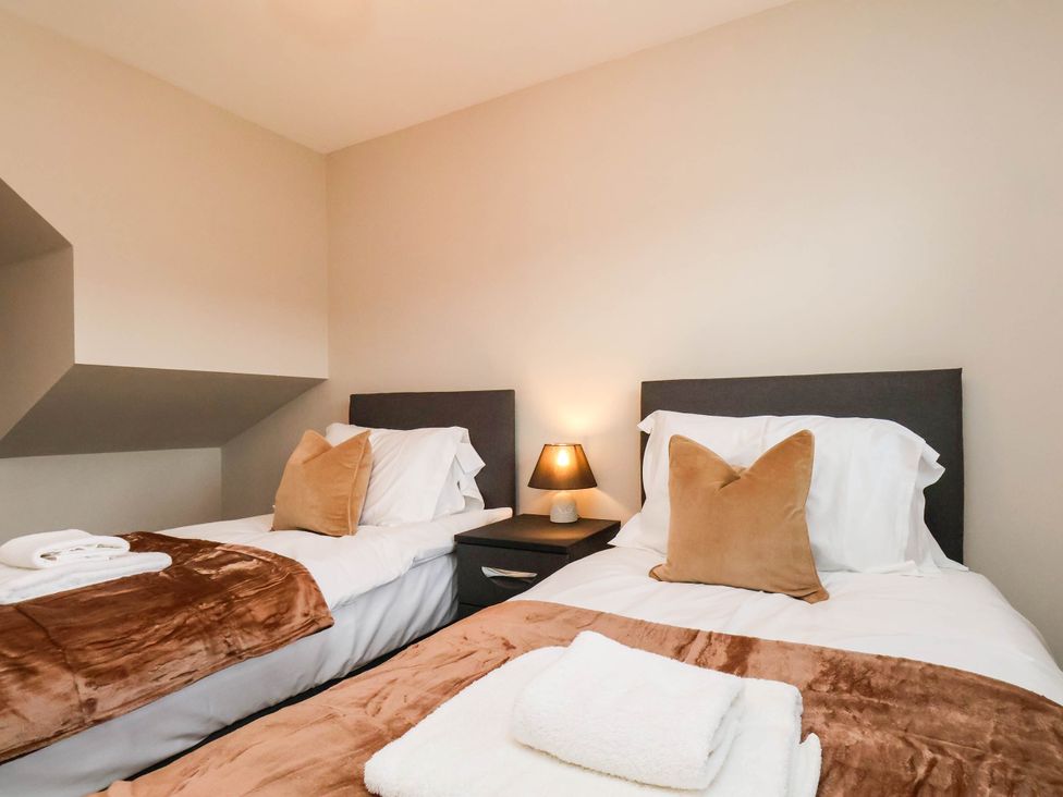 A bedroom with two beds and bedside table at 64 Derwent Road in Whitby